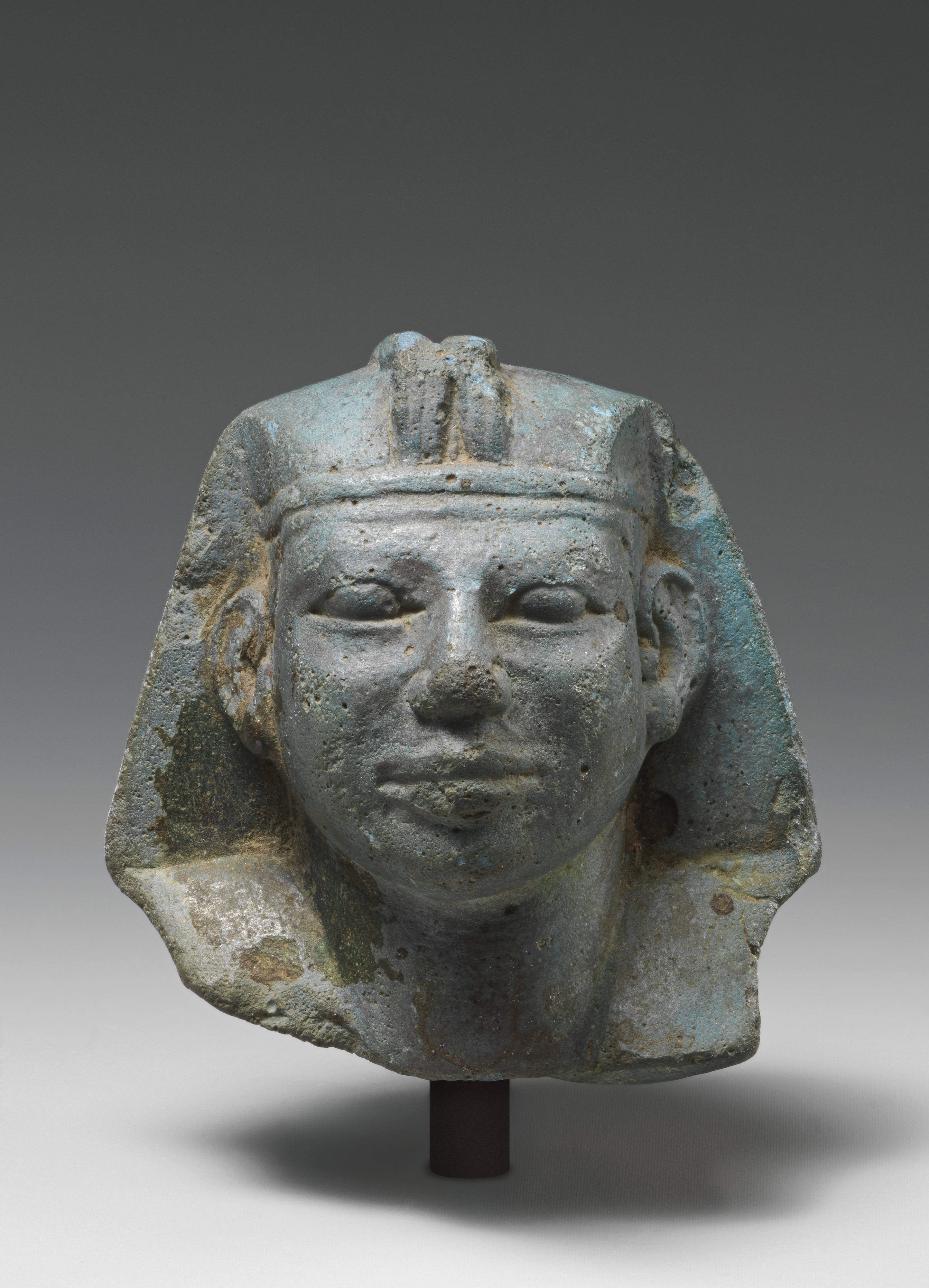 Head of a Kushite King, an ancient Egyptian-blue sculpture, photographed on a gray background